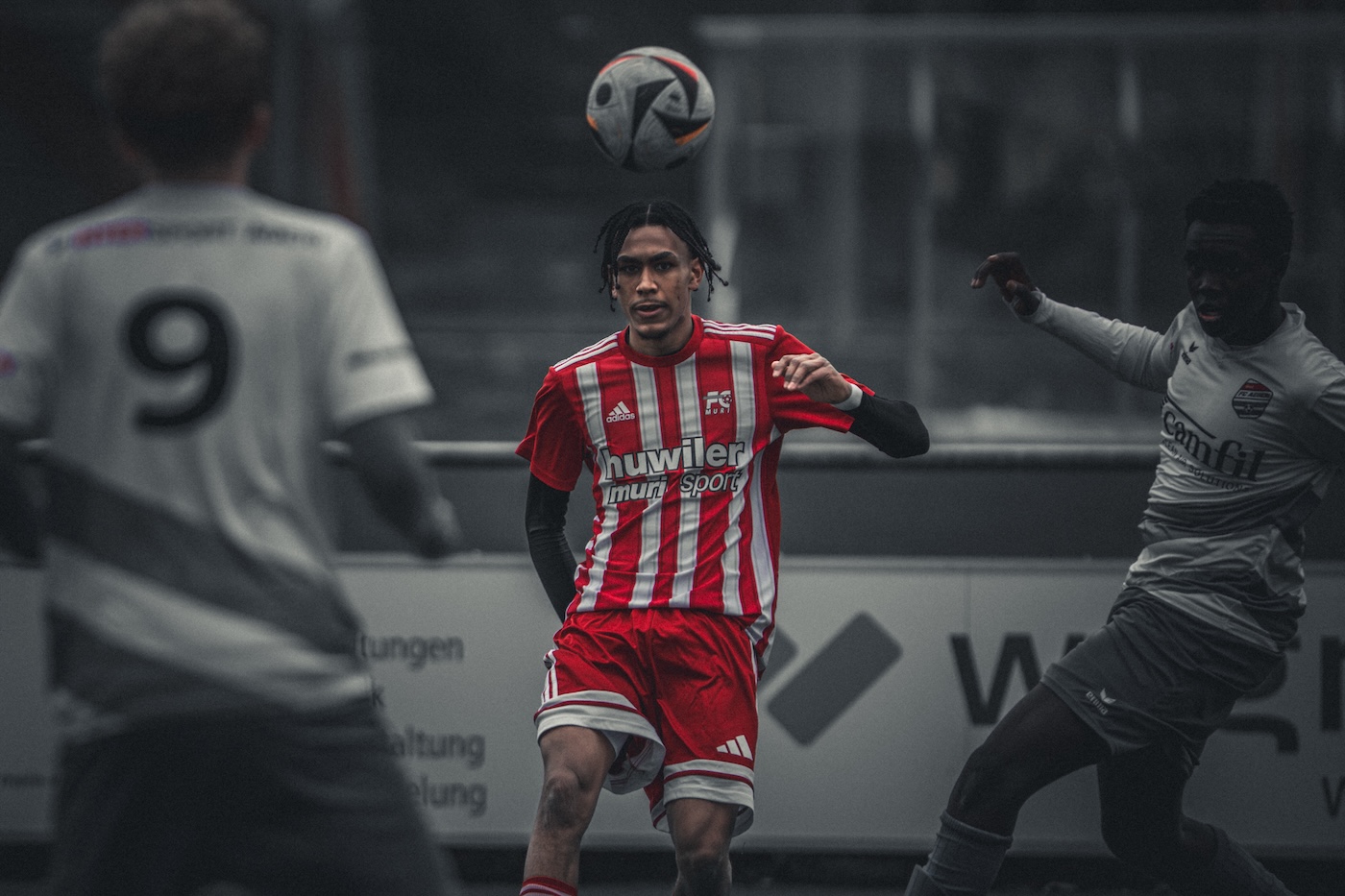 Dramatische Fussballszene mit rotem Spieler im Spielaufbau