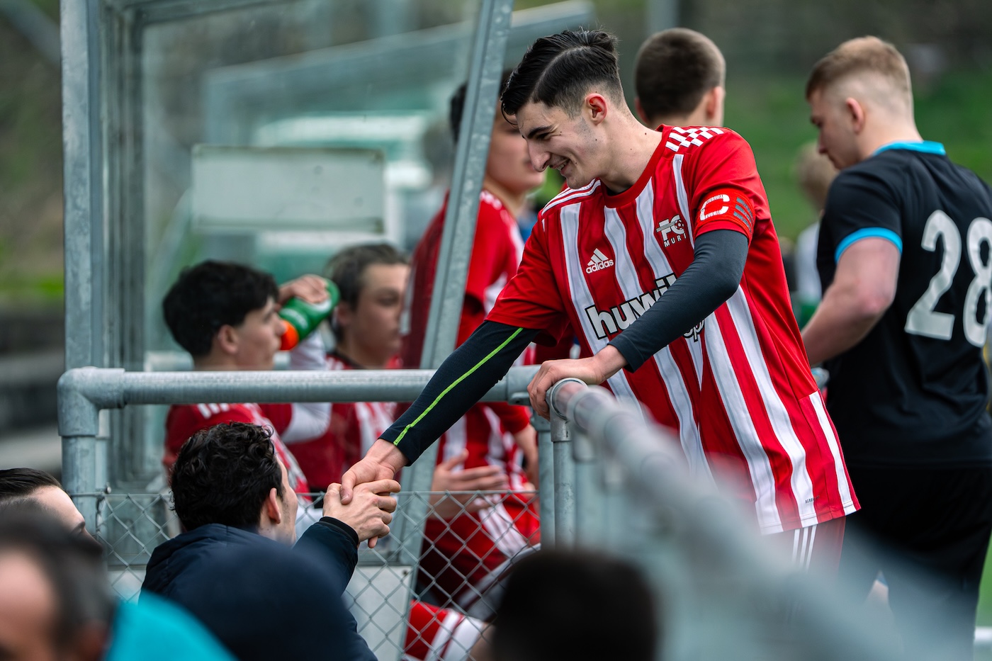 Spieler begrüsst einen Zuschauer am Spielfeldrand
